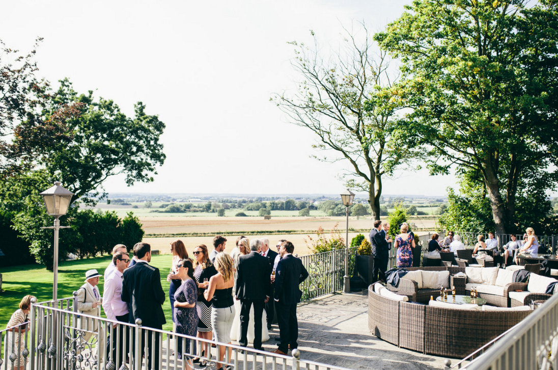 Wedding guests on terrace at West Tower overlooking the cornfields in Summer