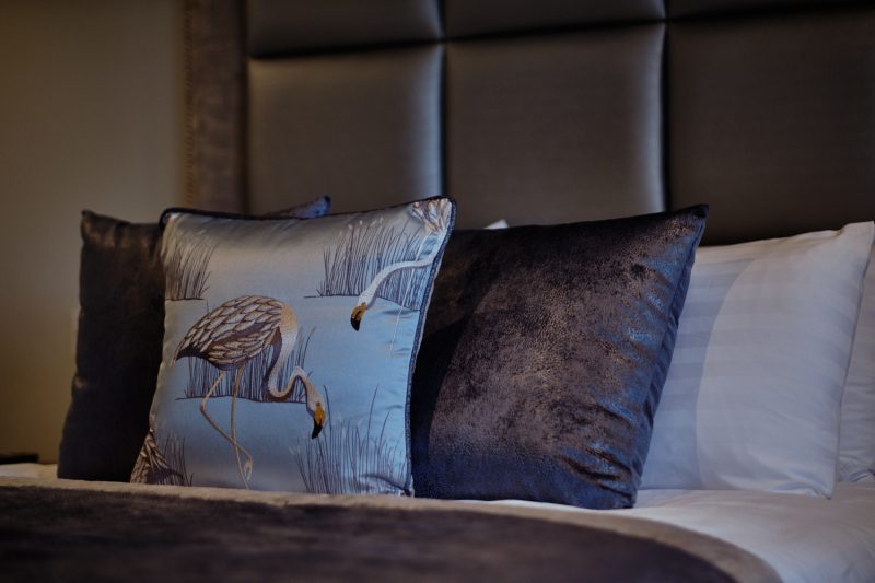A close-up photo of the grey & silver bed cushions with flamigoes in the stable bedrooms at West Tower