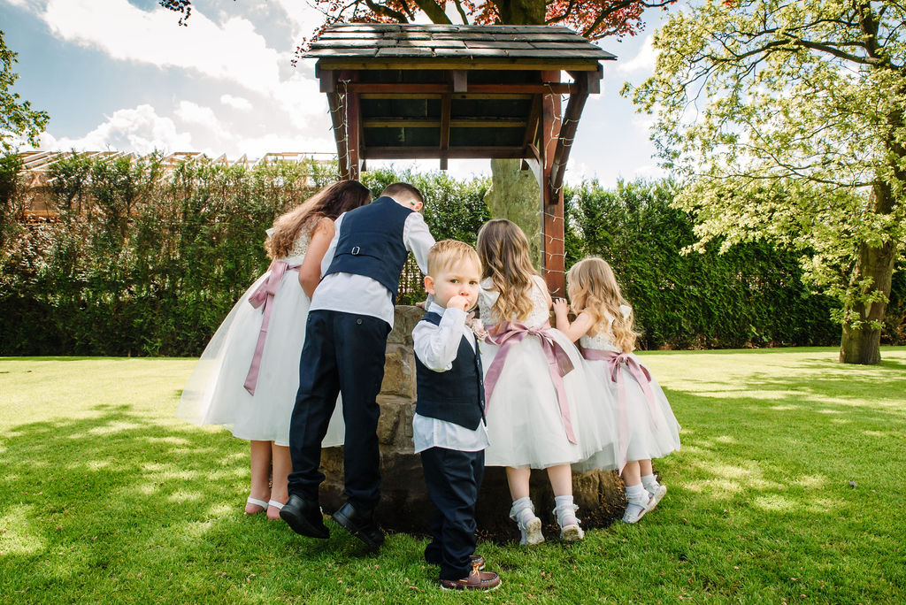 Pageboys & flowergirls looking in the wishing well on the garden at West Tower on a spring day