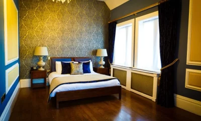 Main house double bedroom at West Tower with blue and gold decor, wooden floor and large windows.