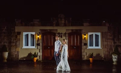 Bride and groom standing in front of two lit cottage doors at West Tower on a wet night