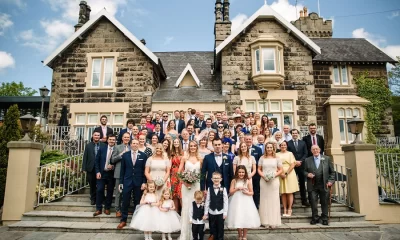 Large wedding party gathered on the front steps of West Tower for a group photograph.