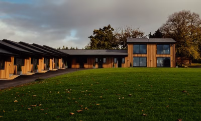 The Stables at West Tower with timber clad lodges and the Cristal Suite overlooking the lawn under a moody sky