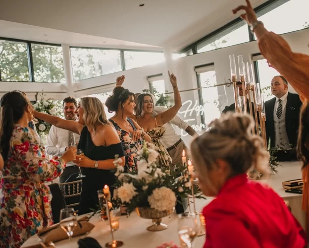 Wedding guests dancing and celebrating around the top table in the Ballroom at West Tower during the evening reception.