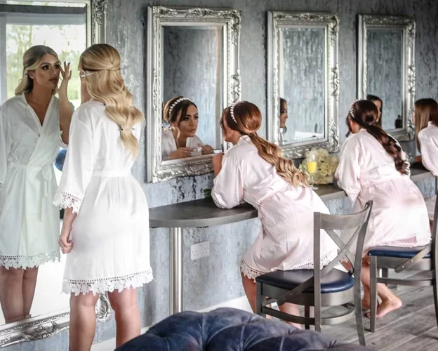 Bride and bridal party getting ready in the Cristal Suite at West Tower, sitting at mirrored dressing tables in matching robes the night before the wedding.