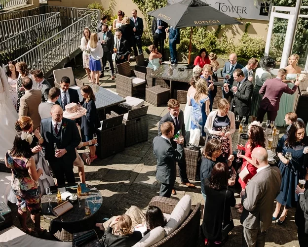 Wedding guests gathered on the terrace outside the Cellar Bar at West Tower during a sunny drinks reception.